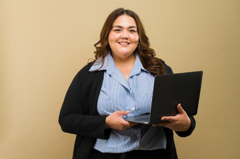 Mujer sonriendo y con un computador en la mano